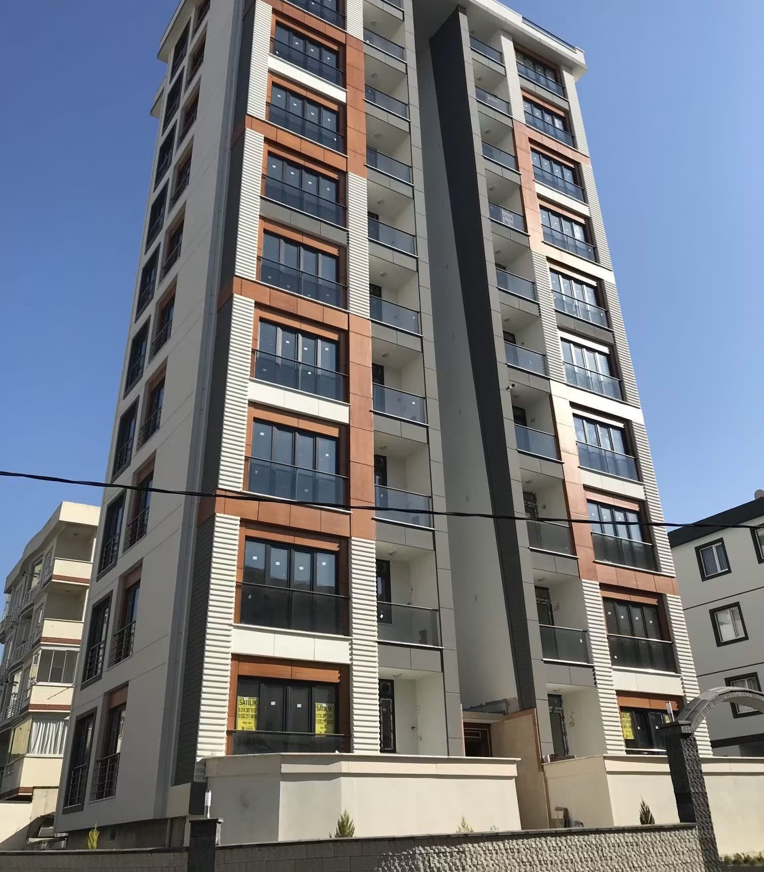 Turuncu ve açık gri cephe kaplamalı konut bloğunun aşağıdan geniş açılı fotoğrafı; kat boyunca balkon dizilimi