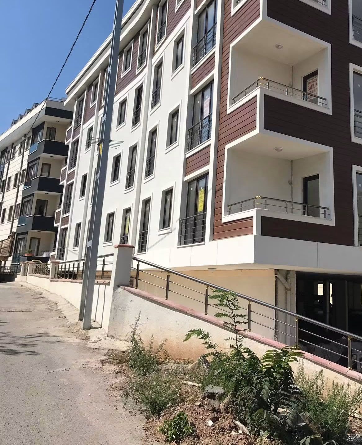 Eğimli sokak üzerinde konumlanan tamamlanmış konut bloğunun cephe fotoğrafı