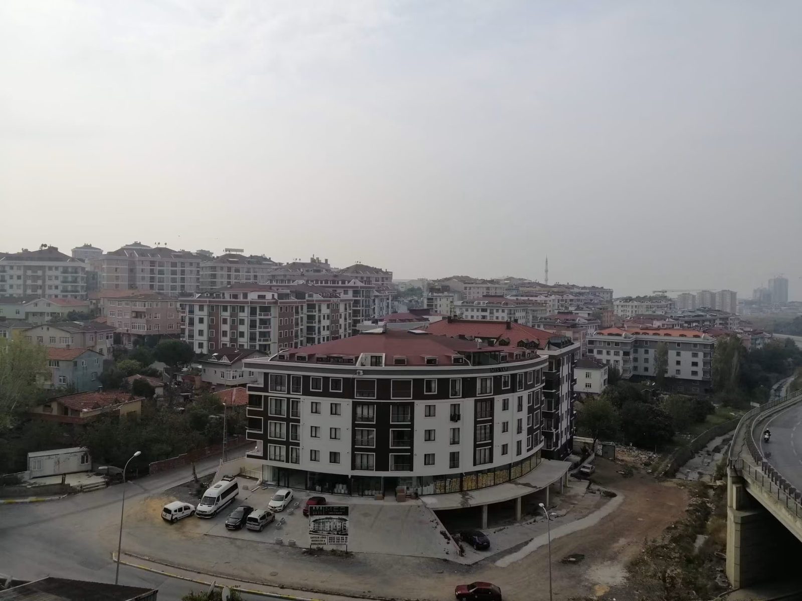 Zümrütevler bölgesinin yüksekten görünümü; tamamlanan yuvarlatılmış köşeli konut bloğu ve çevresindeki yerleşim dokusu