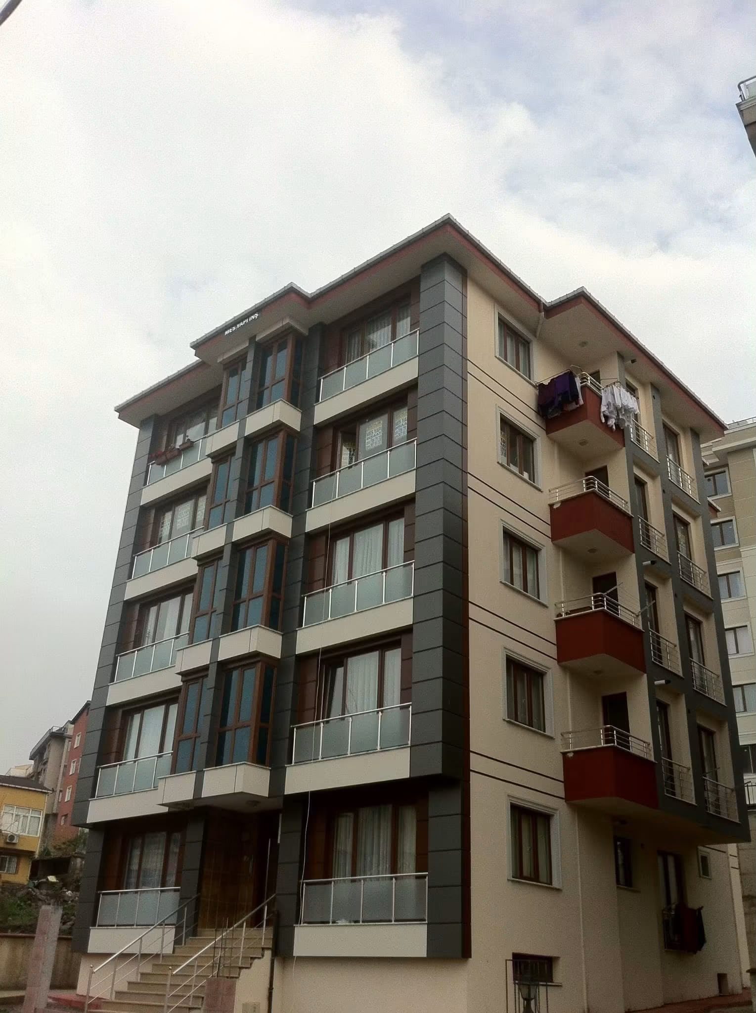 Tamamlanmış Zümrütevler kentsel dönüşüm binasının köşeden fotoğrafı; sıcak tonlu ve gri cephe kaplamaları